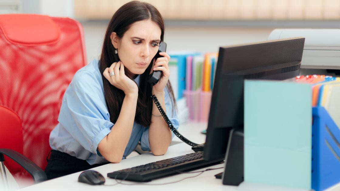 A call center agent with a puzzled expression during a phone call with a customer.