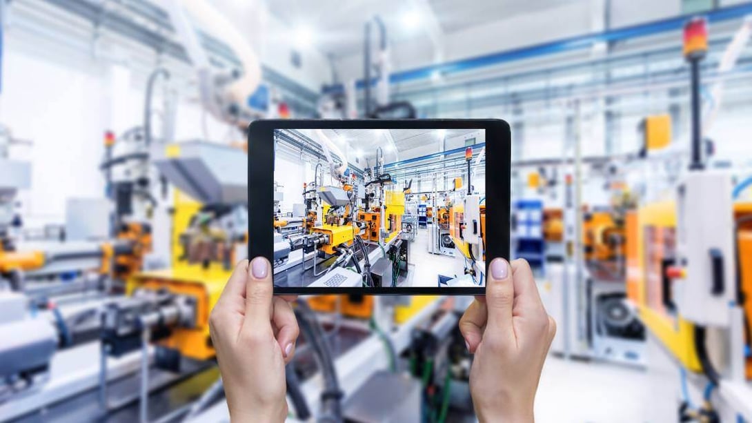 Tablet displaying an IoT device monitoring dashboard in an industrial factory setting
