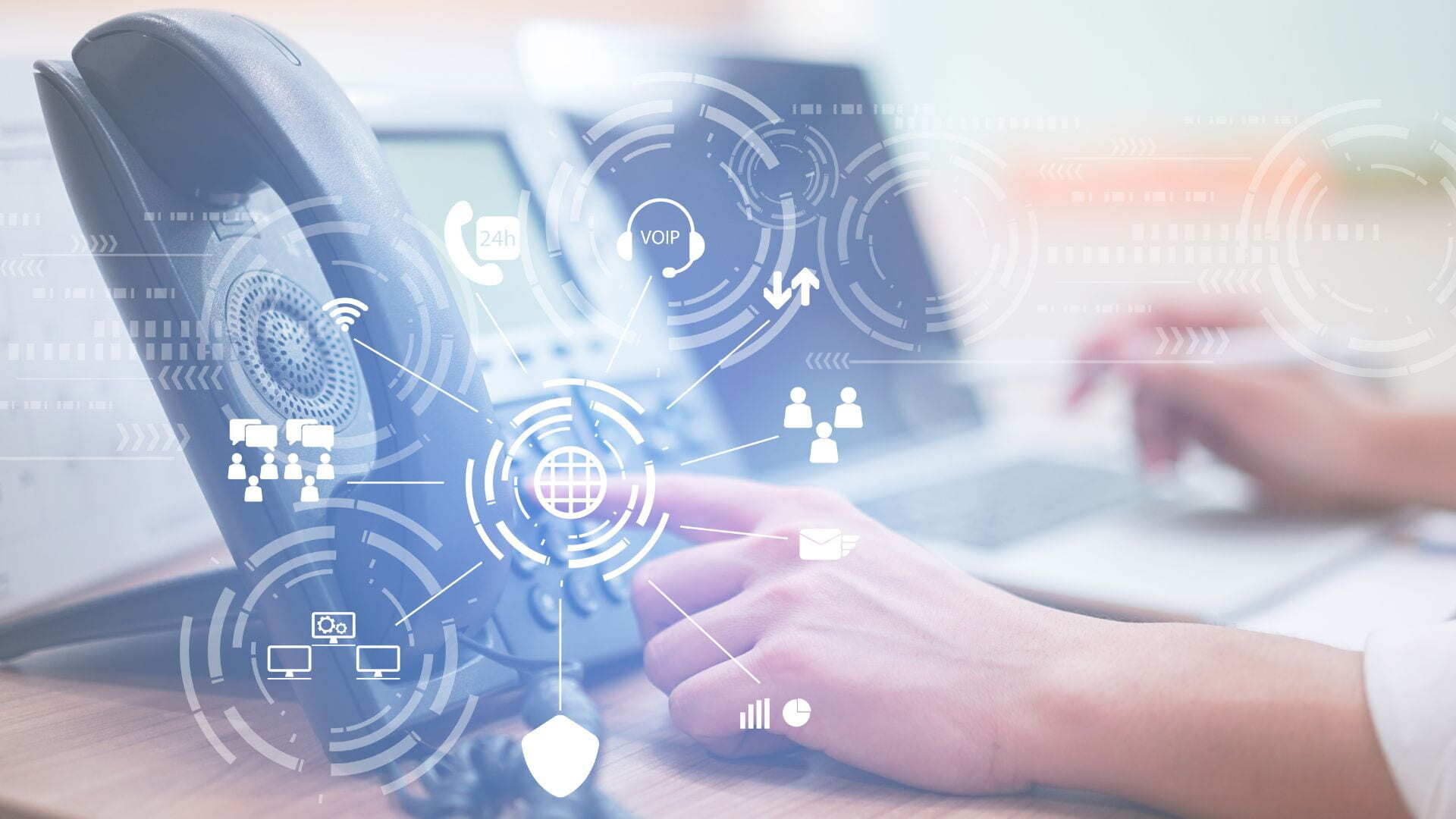Imagem de um ambiente de trabalho com telefone VoIP e laptop, destacando ícones de comunicação, como VoIP, chamadas 24/7 e conectividade global, representando a configuração e uso de DTMF VoIP para empresa