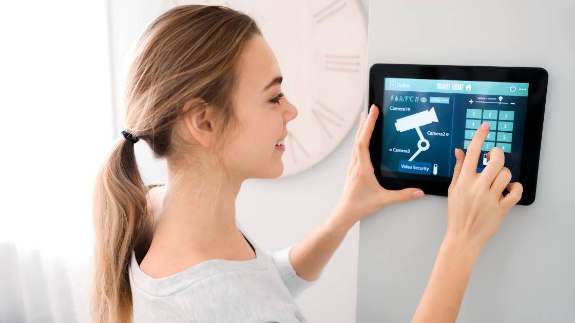 Frau greift über ein Tablet an der Wand auf das Sicherheitssystem zu.