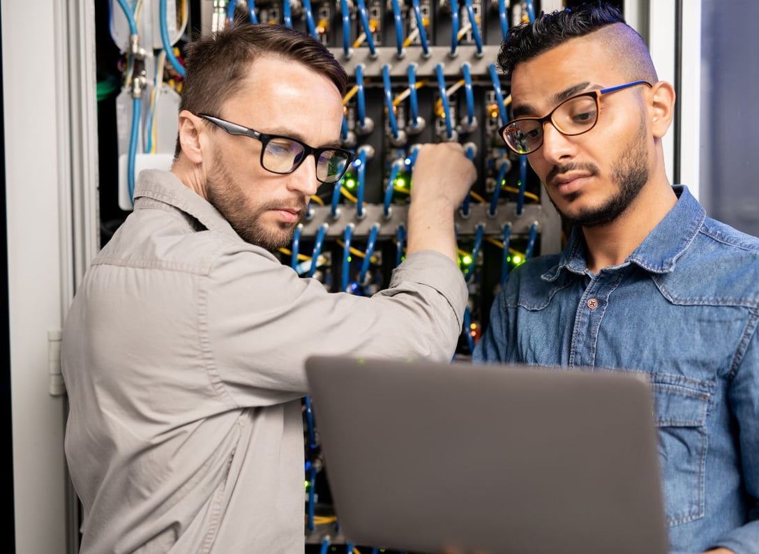 Two IT specialists performing hands-on troubleshooting on a network server during an in-person cloud telephony support visit.